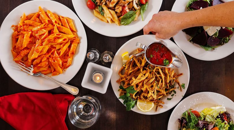 Overhead view of a table laden with Italian dishes, including pasta, salads, and fried calamari.